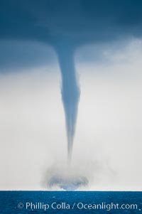 A mature waterspout, seen extending from clouds above to the ocean surface.  A significant disturbance on the ocean is clearly visible, the waterspout has reached is maximum intensity.   Waterspouts are tornadoes that form over water, Great Isaac Island