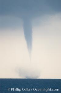 A mature waterspout, seen extending from clouds above to the ocean surface.  A significant disturbance on the ocean is clearly visible, the waterspout has reached is maximum intensity.   Waterspouts are tornadoes that form over water, Great Isaac Island