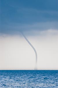 The early stage of a waterspout, in which a funnel descends from clouds down toward the ocean surface.  Note the thin curved vortex of the waterspout, it is not yet mature.  Waterspouts are tornados that form over water