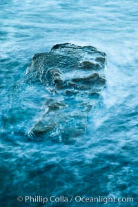 Waves wash over coast rocks.