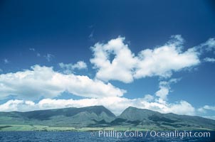 West Maui mountains rise above the coast of Maui, with clouds flanking the ancient eroded remnants of a volcano