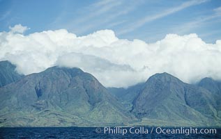 West Maui mountains rise above the coast of Maui, with clouds flanking the ancient eroded remnants of a volcano