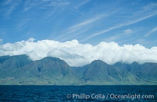 West Maui mountains rise above the coast of Maui, with clouds flanking the ancient eroded remnants of a volcano