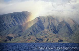 West Maui mountains rise above the coast of Maui, with clouds flanking the ancient eroded remnants of a volcano