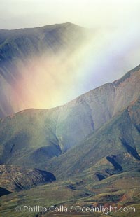 West Maui mountains rise above the coast of Maui, with clouds flanking the ancient eroded remnants of a volcano