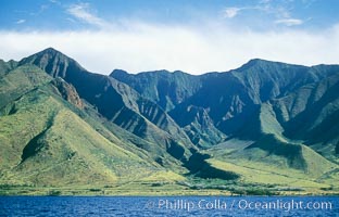 West Maui mountains rise above the coast of Maui, with clouds flanking the ancient eroded remnants of a volcano