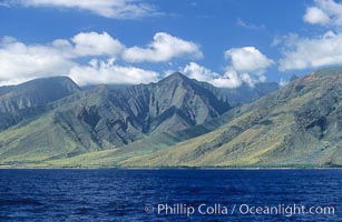 West Maui mountains rise above the coast of Maui, with clouds flanking the ancient eroded remnants of a volcano