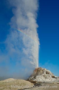 White Dome Geyser, with a faint rainbow visible in its mist, rises to a height of 30 feet or more, and typically erupts with an interval of 15 to 30 minutes.  It is located along Firehole Lake Drive, Lower Geyser Basin, Yellowstone National Park, Wyoming