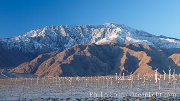 Wind turbines, rise above the flat floor of the San Gorgonio Pass near Palm Springs, with snow covered Mount San Jacinto in the background, provide electricity to Palm Springs and the Coachella Valley