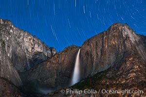 Yosemite Falls and star trails, night sky time exposure of Yosemite Falls waterfall in full spring flow, with star trails arcing through the night sky, Yosemite National Park, California