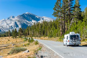 A motorhome passes by alpine meadows and Mammoth Peak as it travels westward along the Tioga Pass road into Tuolumne Meadows in the High Sierra, Yosemite National Park, California