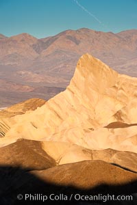 Zabriskie Point, sunrise.  Manly Beacon rises in the center of an eroded, curiously banded area of sedimentary rock, with the Panamint Mountains visible in the distance, Death Valley National Park, California