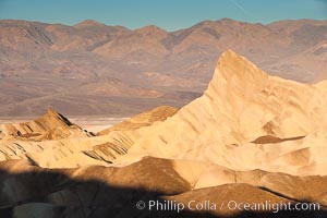 Zabriskie Point, sunrise.  Manly Beacon rises in the center of an eroded, curiously banded area of sedimentary rock, with the Panamint Mountains visible in the distance, Death Valley National Park, California