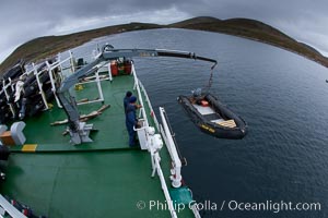 Zodiac boats, are lowered into the ocean from the ship M/V Polar Star in preparation for a day exploring New Island in the Falklands