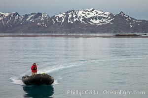 Zodiac inflatable skiff boat, with mountains of South Georgia Island, on the Bay of Isles.