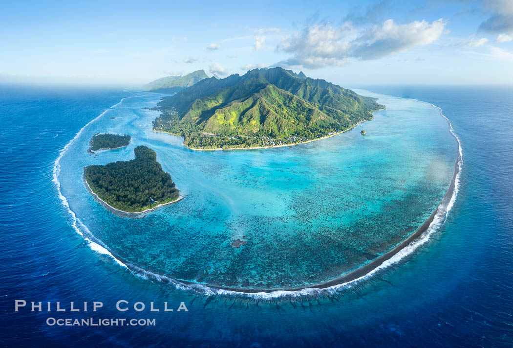 Aerial Photo of the Barrier Reef around Moorea Island, French Polynesia. Motu Tiahura and Motu Fareone are the small islands to the left. The outer reef slope is seen adjacent to deep blue oceanic water with white waves breaking against the reef edge. Next, a wide shallow reef flat occurs dotted with coral bommies. Inside of that, a shallow protected lagoon is formed against the island. Tall, rugged, eroded mountains are seen hinting at the age of the ancient volcano that originally formed the island and that is now sinking back down, leaving the encircling reef behind., natural history stock photograph, photo id 41359
