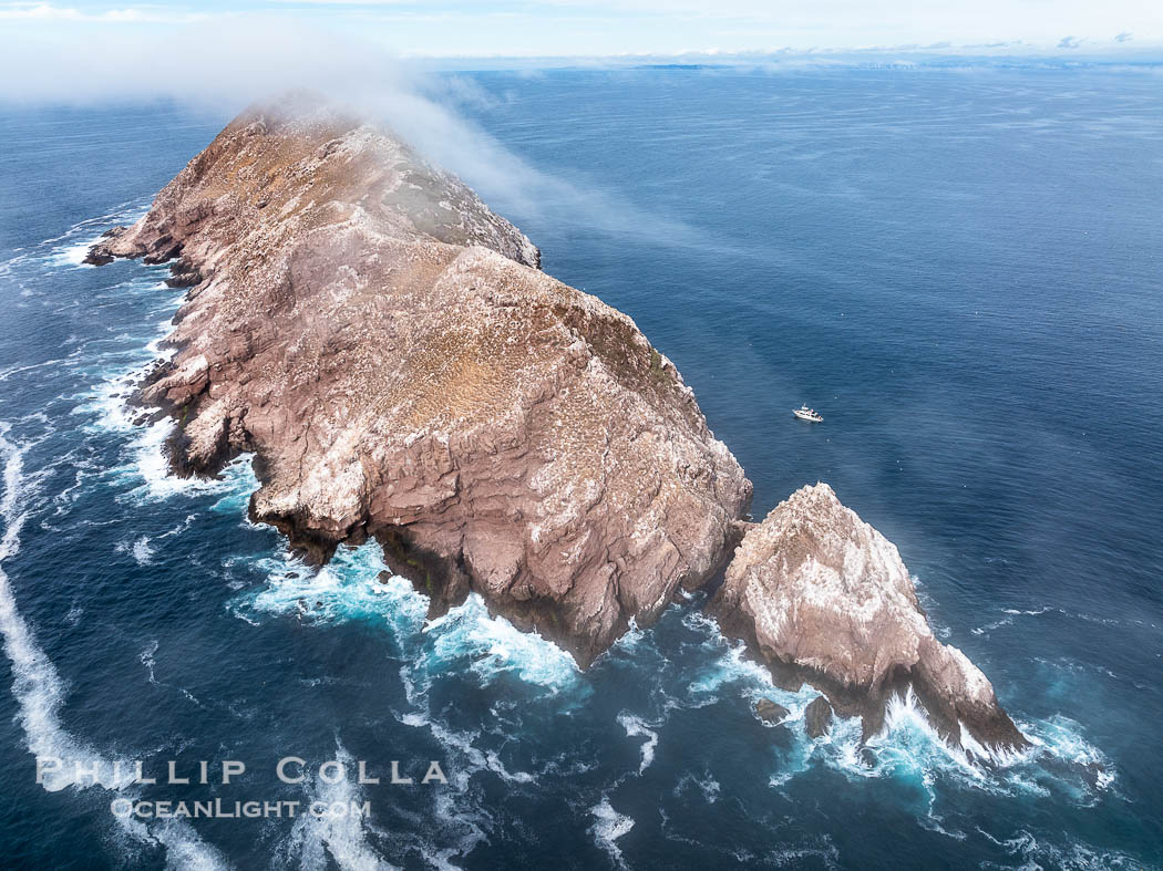 North Coronado Island, Mexico, southern point and keyhole looking north, clouds hugging the top of the island, San Diego in the distance, aerial photograph, Coronado Islands (Islas Coronado) North Coronado Island, Mexico, southern point and keyhole looking north, clouds hugging the top of the island, San Diego in the distance, aerial photograph, Coronado Islands (Islas Coronado)