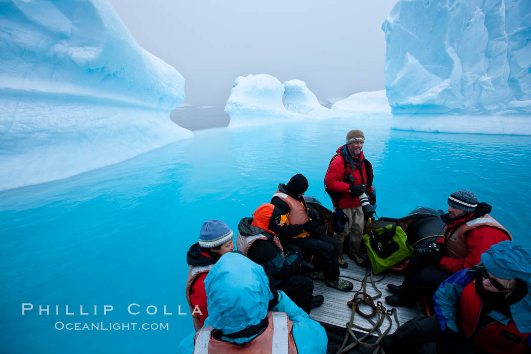 Visitors enjoy an inflatable ride through the strange environs of a bizarrely-shaped iceberg, on a cloudy day. Brown Bluff, Antarctic Peninsula, Antarctica, natural history stock photograph, photo id 24997