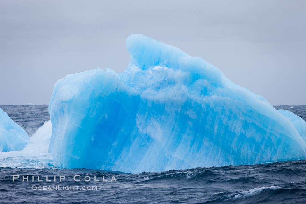 A blue iceberg.  Blue icebergs are blue because the ice from which they are formed has been compressed under such enormous pressure that all gas (bubbles) have been squeezed out, leaving only solid water that takes on a deep blue color. Scotia Sea, Southern Ocean, natural history stock photograph, photo id 24936