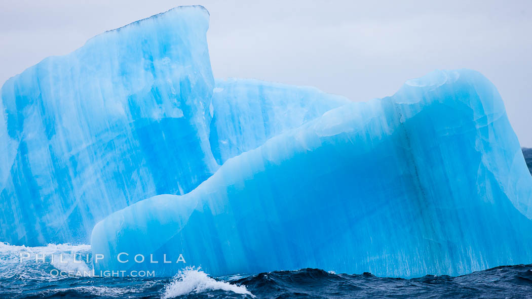 A blue iceberg.  Blue icebergs are blue because the ice from which they are formed has been compressed under such enormous pressure that all gas (bubbles) have been squeezed out, leaving only solid water that takes on a deep blue color. Scotia Sea, Southern Ocean, natural history stock photograph, photo id 24845