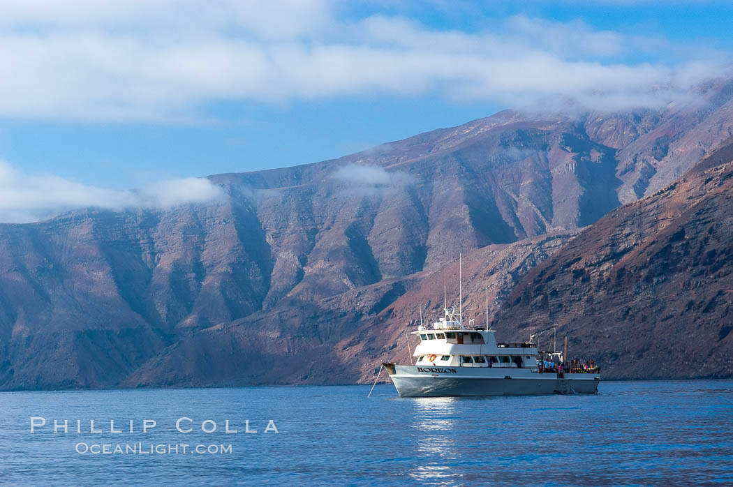 Guadalupe Islands mountainous terrain and sea cliffs tower above the dive boat Horizon while at anchor in Spanish Cove, near the north end of Guadalupe Island (Isla Guadalupe). Baja California, Mexico, natural history stock photograph, photo id 09736