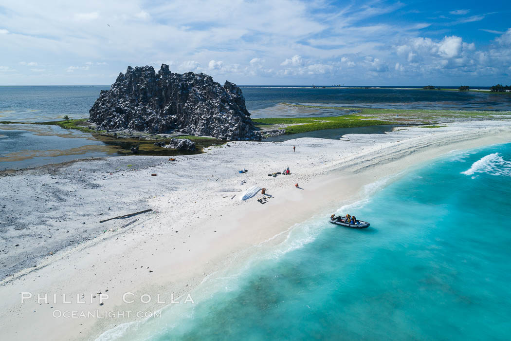 Clipperton Rock, a 95' high volcanic remnant, is the highest point on Clipperton Island, a spectacular coral atoll in the eastern Pacific. The Pacific Ocean encircling the atoll is seen to the right of the white sand beach, and the lagoon inside the atoll is behind Clipperton Rock. By permit HC / 1485 / CAB (France)., natural history stock photograph, photo id 32837