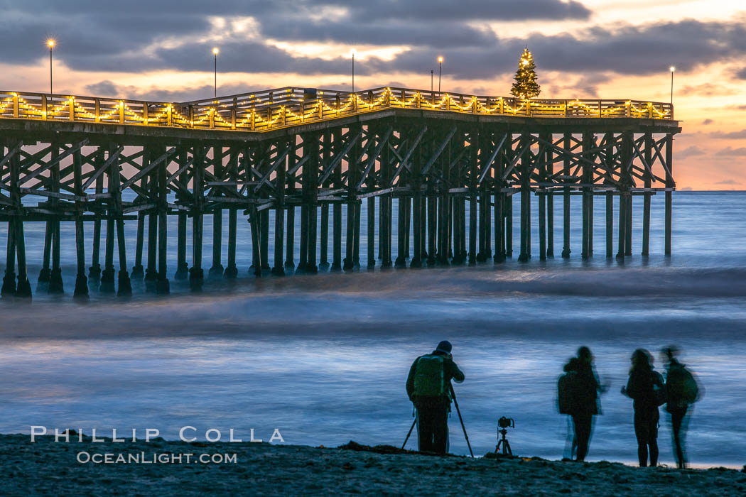 The Crystal Pier, Holiday Lights and Pacific Ocean at sunset, waves blur as they crash upon the sand. Crystal Pier, 872 feet long and built in 1925, extends out into the Pacific Ocean from the town of Pacific Beach., natural history stock photograph, photo id 37561