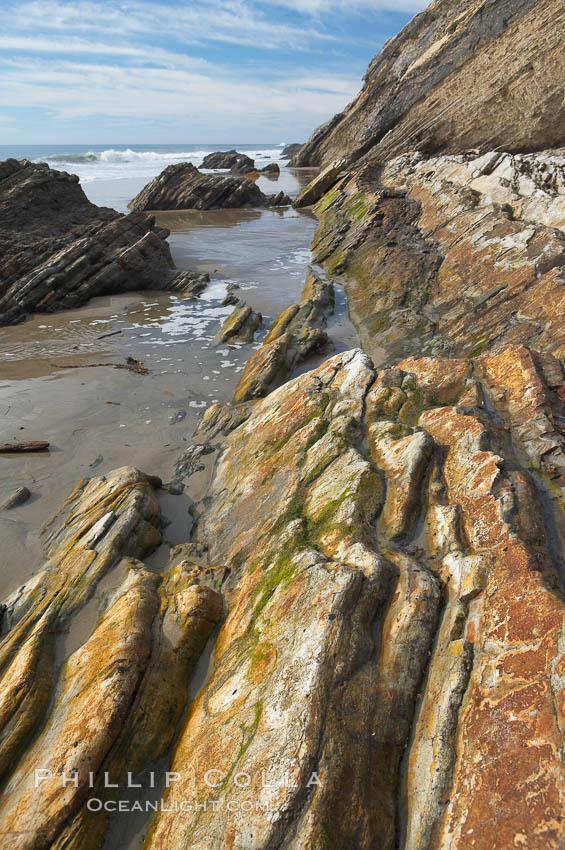 Shale is a fine-grained detrital sedimentary rock formed by the compaction of clay, silt, or mud.  Shale is formed when mud is pressed into rock over millions of years and often breaks into big flat pieces. Here layers of shale emerge from the sand and cliffs at Gaviota State Beach north of Santa Barbara. California, USA, natural history stock photograph, photo id 14894