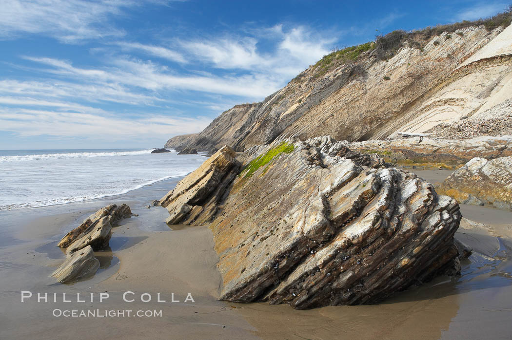 Shale is a fine-grained detrital sedimentary rock formed by the compaction of clay, silt, or mud.  Shale is formed when mud is pressed into rock over millions of years and often breaks into big flat pieces. Here layers of shale emerge from the sand and cliffs at Gaviota State Beach north of Santa Barbara. California, USA, natural history stock photograph, photo id 14896