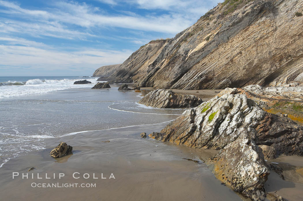 Shale is a fine-grained detrital sedimentary rock formed by the compaction of clay, silt, or mud.  Shale is formed when mud is pressed into rock over millions of years and often breaks into big flat pieces. Here layers of shale emerge from the sand and cliffs at Gaviota State Beach north of Santa Barbara. California, USA, natural history stock photograph, photo id 14895