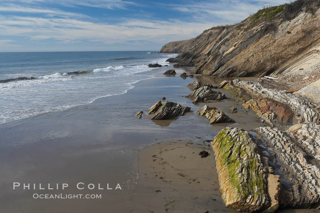 Shale is a fine-grained detrital sedimentary rock formed by the compaction of clay, silt, or mud.  Shale is formed when mud is pressed into rock over millions of years and often breaks into big flat pieces. Here layers of shale emerge from the sand and cliffs at Gaviota State Beach north of Santa Barbara. California, USA, natural history stock photograph, photo id 14899