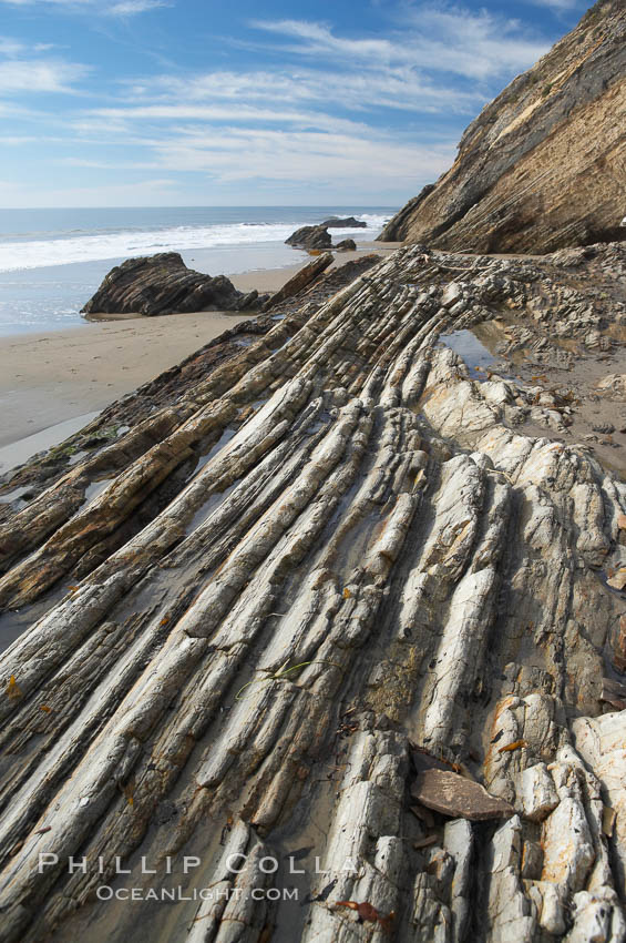 Shale is a fine-grained detrital sedimentary rock formed by the compaction of clay, silt, or mud.  Shale is formed when mud is pressed into rock over millions of years and often breaks into big flat pieces. Here layers of shale emerge from the sand and cliffs at Gaviota State Beach north of Santa Barbara. California, USA, natural history stock photograph, photo id 14893