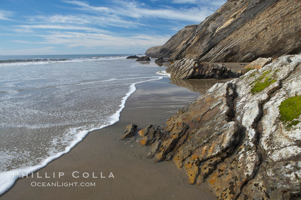 Shale is a fine-grained detrital sedimentary rock formed by the compaction of clay, silt, or mud.  Shale is formed when mud is pressed into rock over millions of years and often breaks into big flat pieces. Here layers of shale emerge from the sand and cliffs at Gaviota State Beach north of Santa Barbara. California, USA, natural history stock photograph, photo id 14897