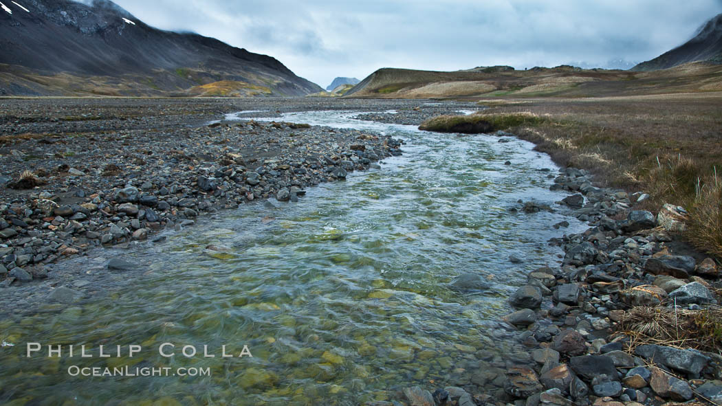 Glacial melt waters, runoff, flows across an alluvial flood plain between mountains, on its way to Stromness Bay. Stromness Harbour, South Georgia Island, natural history stock photograph, photo id 24587