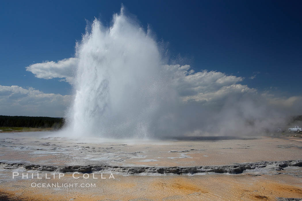 Great Fountain Geyser erupting.  Great Fountain Geyser, a fountain-type geyser, can reach heights of 200 feet, one of the largest geysers in the world.  It has a large vent (16 feet across) situated amid wide sinter terraces that act as reflecting pools as the geyser slows fills prior to its eruption.  Its interval and duration vary widely.  It typically erupts in a series of bursts, each separately by a few minutes.  Firehole Lake Drive. Lower Geyser Basin, Yellowstone National Park, Wyoming, USA, natural history stock photograph, photo id 13556