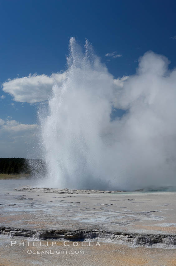 Great Fountain Geyser erupting.  Great Fountain Geyser, a fountain-type geyser, can reach heights of 200 feet, one of the largest geysers in the world.  It has a large vent (16 feet across) situated amid wide sinter terraces that act as reflecting pools as the geyser slows fills prior to its eruption.  Its interval and duration vary widely.  It typically erupts in a series of bursts, each separately by a few minutes.  Firehole Lake Drive. Lower Geyser Basin, Yellowstone National Park, Wyoming, USA, natural history stock photograph, photo id 13557