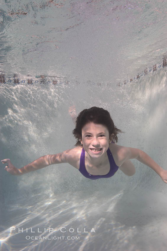 Having just leapt into a pool, this smiling kid emerges from a cloud of bubbles and smiles for the camera., natural history stock photograph, photo id 07753