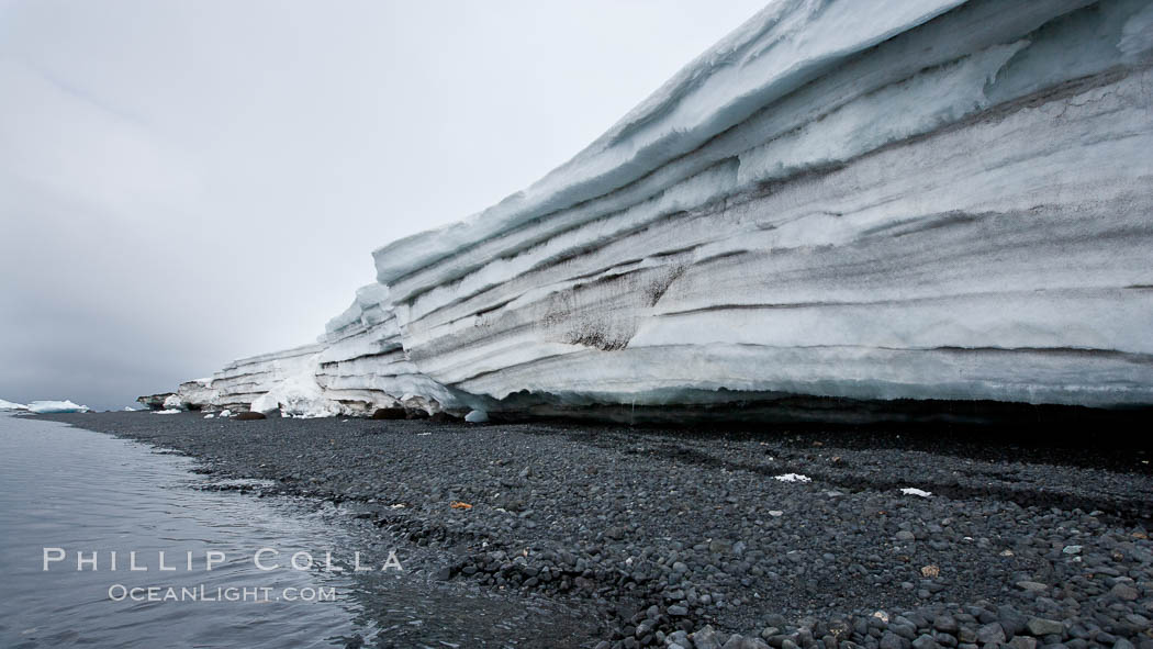 Horizontal striations and layers in packed snow, melting and overhanging, seen from the edge of the snowpack, along a rocky beach. Brown Bluff, Antarctic Peninsula, Antarctica, natural history stock photograph, photo id 24871