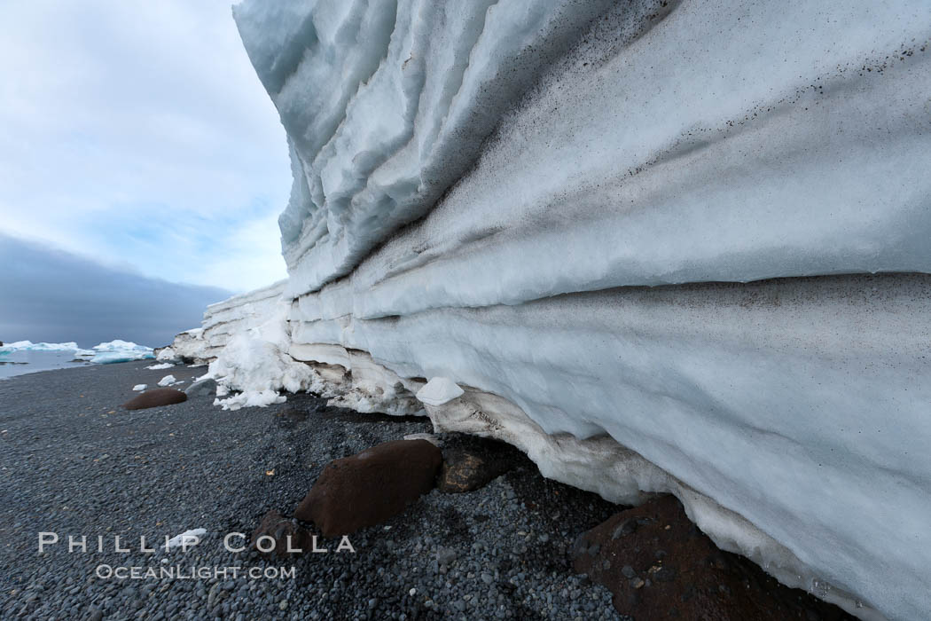 Horizontal striations and layers in packed snow, melting and overhanging, seen from the edge of the snowpack, along a rocky beach. Brown Bluff, Antarctic Peninsula, Antarctica, natural history stock photograph, photo id 24873
