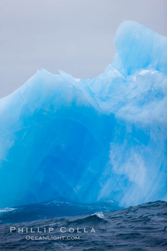 A blue iceberg.  Blue icebergs are blue because the ice from which they are formed has been compressed under such enormous pressure that all gas (bubbles) have been squeezed out, leaving only solid water that takes on a deep blue color. Scotia Sea, Southern Ocean, natural history stock photograph, photo id 24935