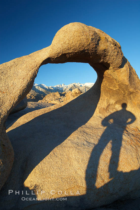 The long shadow of a hiker lies on Mobius Arch, a natural stone arch in the Alabama Hills. Alabama Hills Recreational Area, California, USA, natural history stock photograph, photo id 21733
