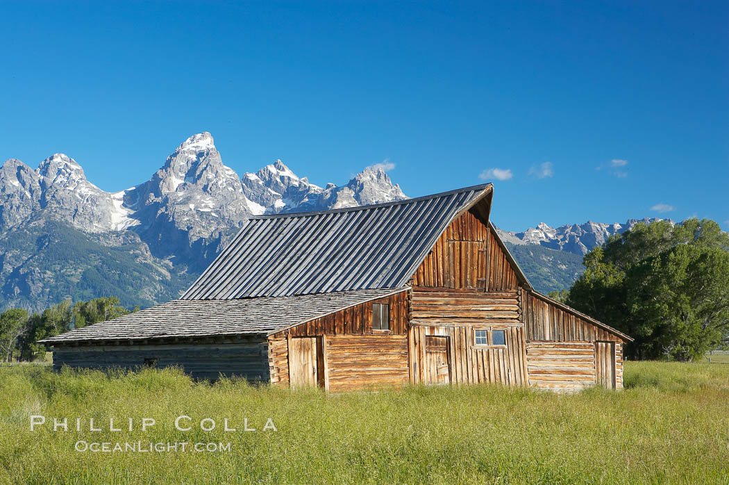 An old barn at Mormon Row is lit by the morning sun with the Teton Range rising in the distance. Grand Teton National Park, Wyoming, USA, natural history stock photograph, photo id 12997
