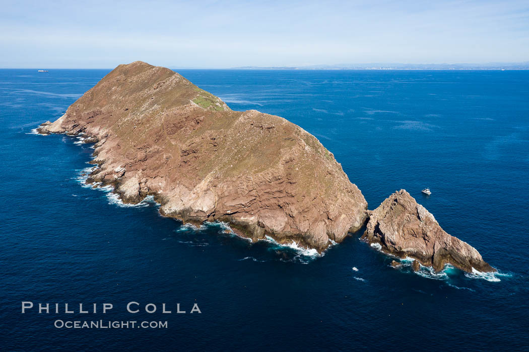 Aerial Photo of North Coronado Island, Baja California, Mexico, viewed from the southwest. The Keyhole, a spectacular narrow cut and underwater tunnel through the island, is seen at the narrow neck of the island. The San Diego and Tijuana coastline is visible in the distance. Coronado Islands (Islas Coronado), natural history stock photograph, photo id 35896