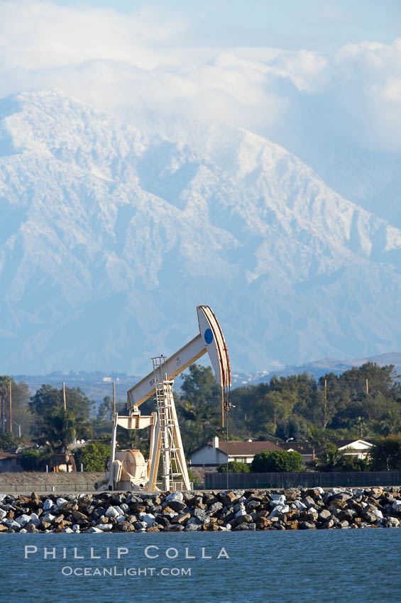 Oil pump, tract homes and snow-covered San Bernardino mountains, viewed from Bolsa Chica State Ecological Reserve. Huntington Beach, California, USA, natural history stock photograph, photo id 19917