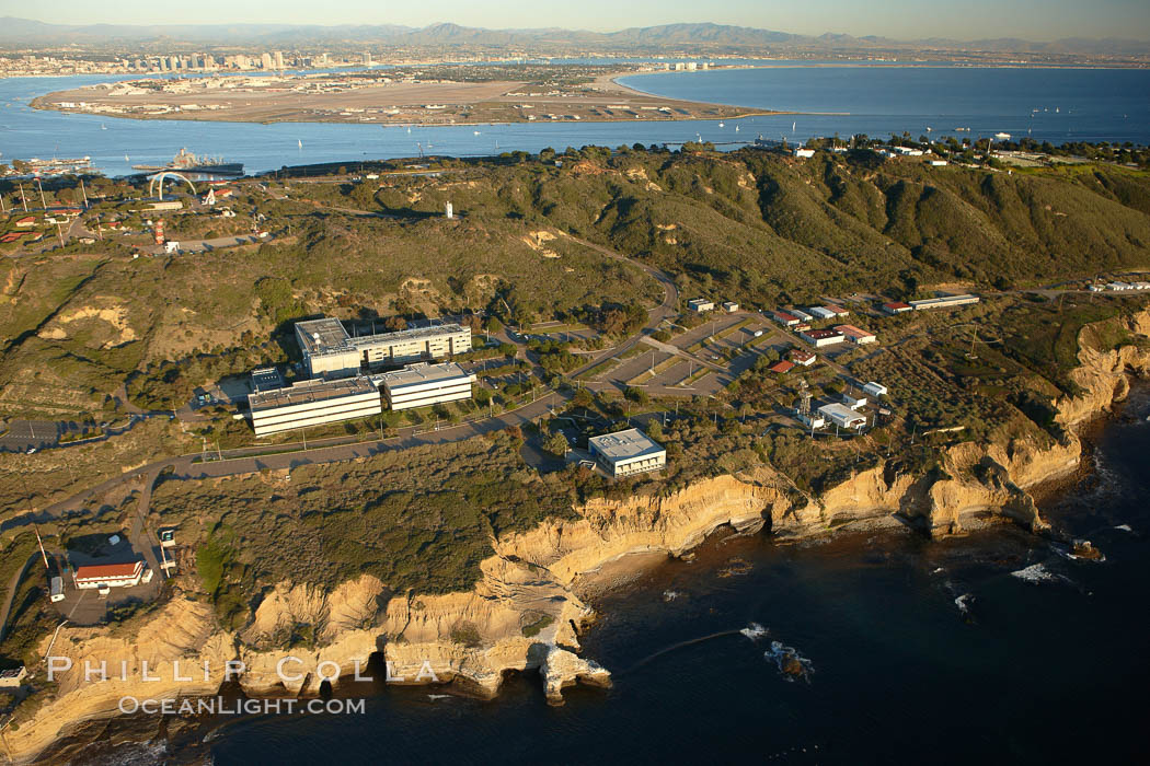 Point Loma peninsula, with scalloped sandstone cliffs edging the Pacific Ocean.  San Diego Bay, Coronado Island and the high rises of downtown San Diego are seen beyond.  Navy facilities, including SPAWAR (Space and Naval Warfare) building 600 in left center, are scattered along this section of Point Loma. California, USA, natural history stock photograph, photo id 22363