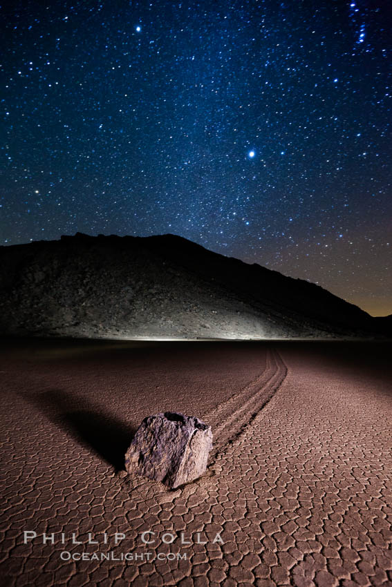 Racetrack sailing stone and Milky Way, at night. A sliding rock of the Racetrack Playa. The sliding rocks, or sailing stones, move across the mud flats of the Racetrack Playa, leaving trails behind in the mud. The explanation for their movement is not known with certainty, but many believe wind pushes the rocks over wet and perhaps icy mud in winter. Death Valley National Park, California, USA, natural history stock photograph, photo id 27640