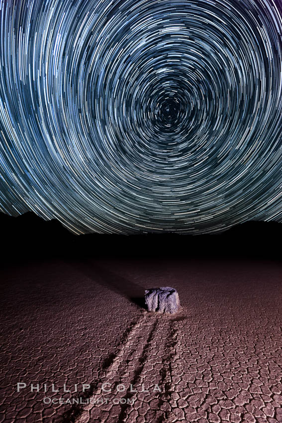 Racetrack sailing stone and star trails.  A sliding rock of the Racetrack Playa. The sliding rocks, or sailing stones, move across the mud flats of the Racetrack Playa, leaving trails behind in the mud. The explanation for their movement is not known with certainty, but many believe wind pushes the rocks over wet and perhaps icy mud in winter. Death Valley National Park, California, USA, natural history stock photograph, photo id 27670