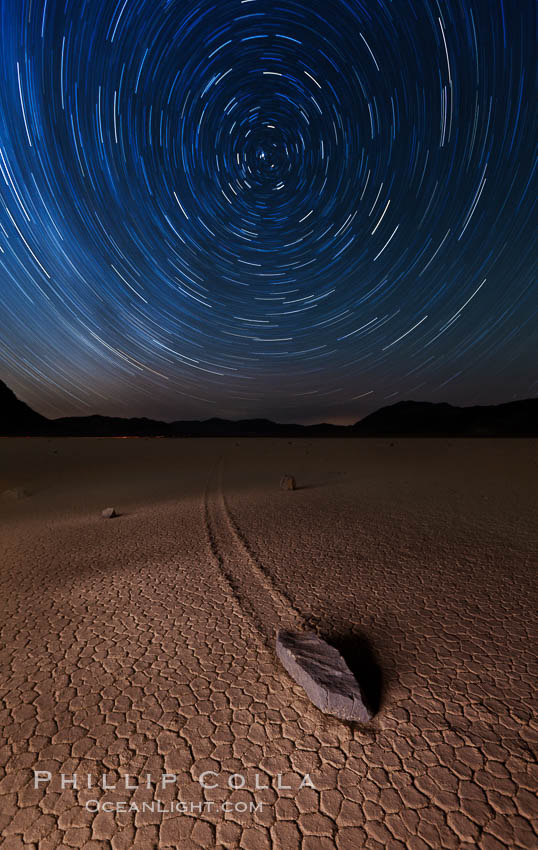 Racetrack sailing stone and star trails.  A sliding rock of the Racetrack Playa. The sliding rocks, or sailing stones, move across the mud flats of the Racetrack Playa, leaving trails behind in the mud. The explanation for their movement is not known with certainty, but many believe wind pushes the rocks over wet and perhaps icy mud in winter. Death Valley National Park, California, USA, natural history stock photograph, photo id 27667