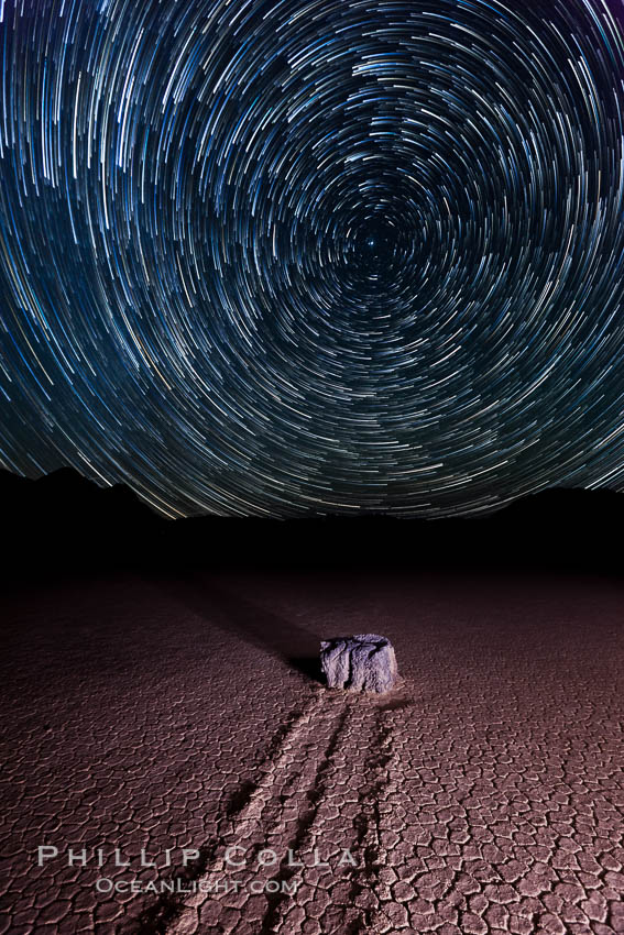 Racetrack sailing stone and star trails.  A sliding rock of the Racetrack Playa. The sliding rocks, or sailing stones, move across the mud flats of the Racetrack Playa, leaving trails behind in the mud. The explanation for their movement is not known with certainty, but many believe wind pushes the rocks over wet and perhaps icy mud in winter. Death Valley National Park, California, USA, natural history stock photograph, photo id 27671