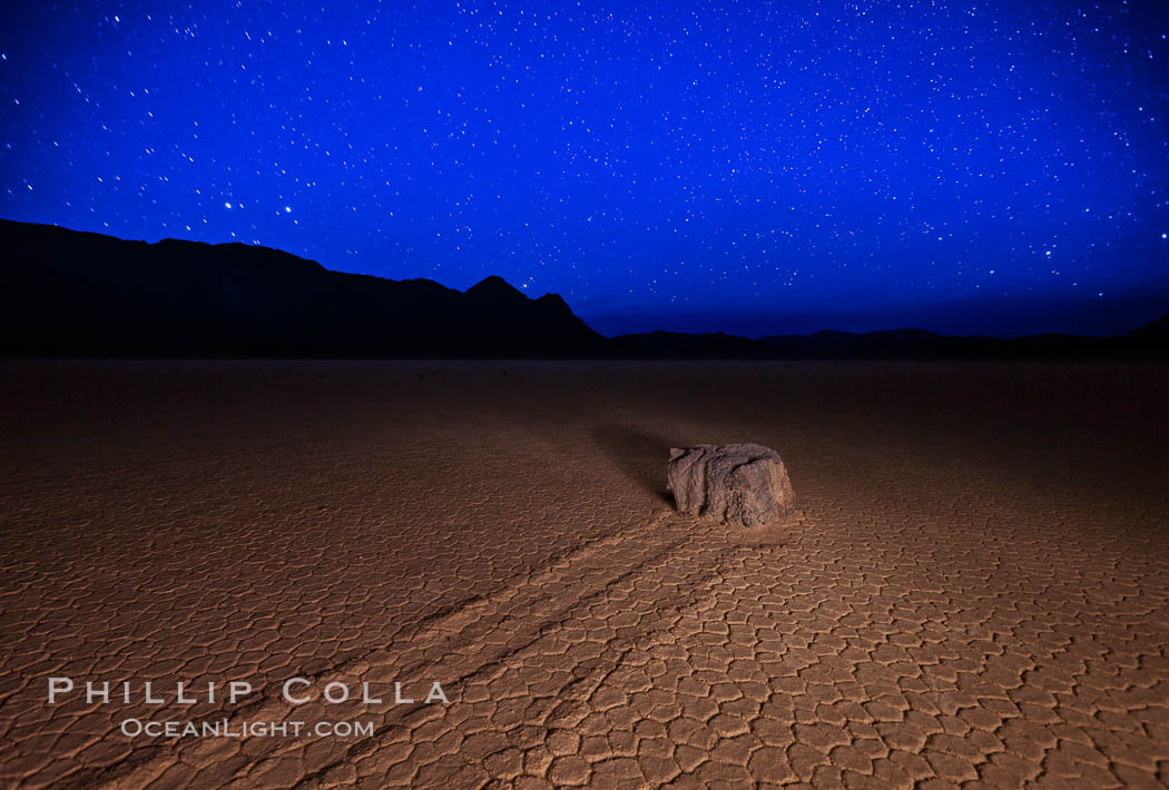 Racetrack sailing stone and stars at night. A sliding rock of the Racetrack Playa. The sliding rocks, or sailing stones, move across the mud flats of the Racetrack Playa, leaving trails behind in the mud. The explanation for their movement is not known with certainty, but many believe wind pushes the rocks over wet and perhaps icy mud in winter. Death Valley National Park, California, USA, natural history stock photograph, photo id 27636